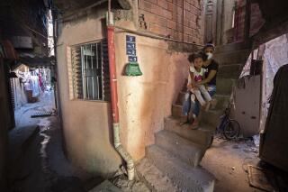 Ana Carolina Silva, who lost her job during the COVID-19 pandemic, sits with her daughter Cataleia outside her home in the Paraisopolis favela of Sao Paulo, Brazil, Monday, May 24, 2021. (AP Photo/Andre Penner)