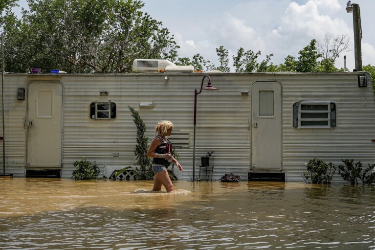 A woman who identified herself only as Lisa Marie checks on an elderly resident in an RV after neighbors were evacuated due to severe flooding in Channel View, Texas, Saturday, May 4, 2024.  (Raquel Natalichio/Houston Chronicle, via AP)