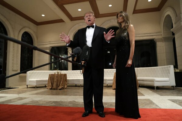 President Donald Trump speaks to the media about the situation at the U.S. embassy in Baghdad, from his Mar-a-Lago property, Tuesday, Dec. 31, 2019, in Palm Beach, Fla., as Melania Trump stands next to him. (AP Photo/ Evan Vucci)