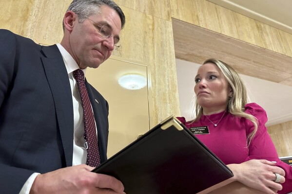 North Dakota Attorney General Drew Wrigley and Republican state Rep. Emily O'Brien confer during a break in a meeting of a legislative audit panel on Tuesday, Dec. 19, 2023, at the state Capitol in Bismarck, N.D. A special prosecutor has declined to press charges, Thursday, Feb. 29, 2024, in connection with the deletion of late North Dakota Attorney General Wayne Stenehjem's state government email account days after he died in 2022.(AP Photo/Jack Dura)