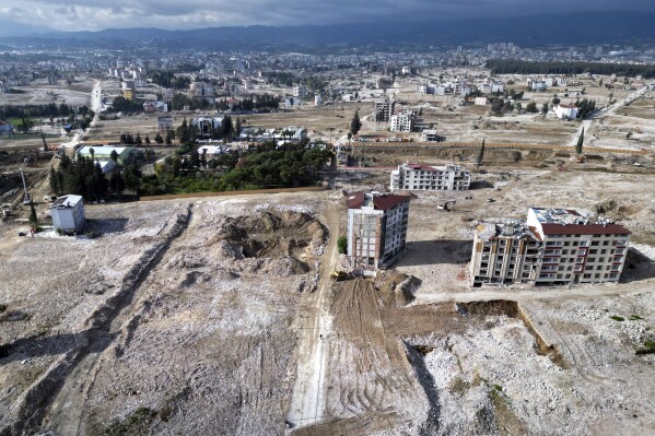 This Thursday, Jan. 11, 2024 photo shows an arial view of terrain that were cleared of rubble from buildings that were destroyed by the Feb. 6, 2023 powerful earthquake in the city of Antakya, southern Turkey. A year after the quake, many of the collapsed or seriously damaged buildings in hard-hit Antakya have been torn down and the debris removed. (AP Photo/Khalil Hamra)