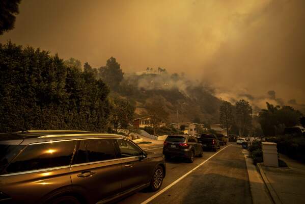 A line of vehicles crowds the road as residents flee from the Palisades Fire in the Pacific Palisades neighborhood of Los Angeles, Tuesday, Jan. 7, 2025. (AP Photo/Ethan Swope)