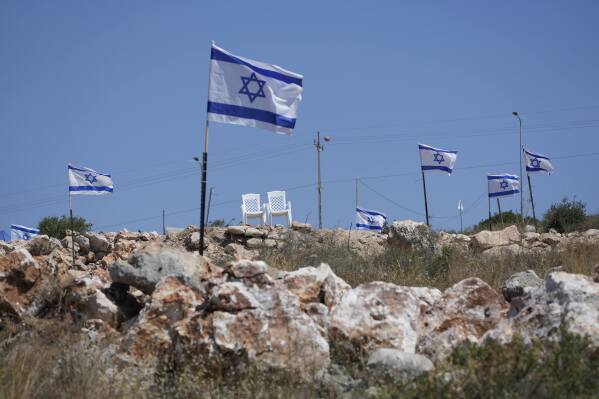 Israeli flags fly flutter on top of a hill that is adjacent to Palestinian properties that were under attack by Israeli settlers overnight, leaving several burnt vehicles and damaged homes, residents said, in the West Bank village of Bruqin, near Salfit, Friday, May 23, 2025. (AP Photo/Nasser Nasser)