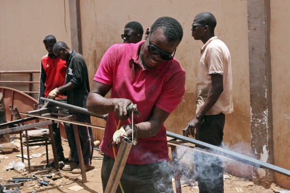 Soumaila Traoré, a 30-years-old welder, and his workers, work under a blazing sun. in Bamako, Mali, Thursday, April, 18, 2024. On Thursday, temperatures in Bamako reached 44 degrees Celsius (111 Fahrenheit) and weather forecasts say it's not letting up anytime soon. (AP Photo/Baba Ahmed)