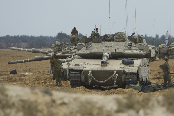 Israeli soldiers work on tanks and APCs in a staging area near the border with the Gaza Strip in southern Israel on Thursday, May 15, 2025, (AP Photo/Ariel Schalit)