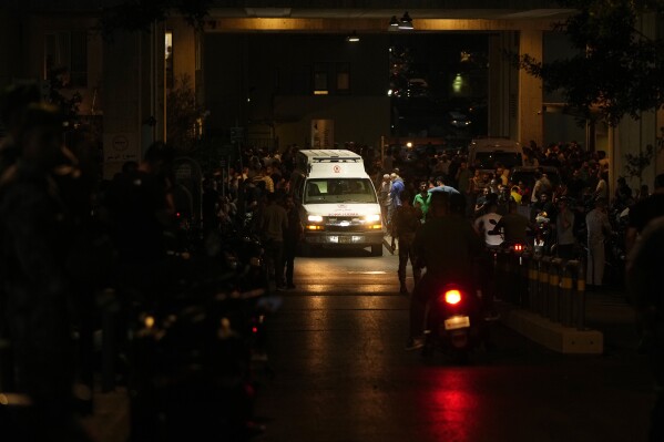 People gather around an ambulance carrying wounded people whose handheld pager exploded, at the emergency entrance of the American University hospital in Beirut, Lebanon, Tuesday, Sept. 17, 2024. (AP Photo/Hassan Ammar)