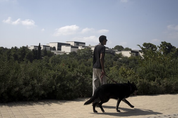 A man walks his dog past the Israel Museum in Jerusalem, Friday, Oct. 6, 2023. Israeli police have arrested an American tourist at the Israel Museum in Jerusalem after he hurled works of art to the floor, damaging two second-century Roman statues. The vandalism late Thursday raised questions about the safety of Israel's priceless collections, as well as concern about a rise in attacks on cultural heritage in Jerusalem. (AP Photo/Maya Alleruzzo)