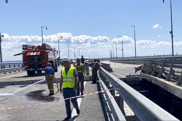 In this image from a video released on Wednesday, July 19, 2023 by Russian National Antiterrorism Committee, employees work at the damaged parts of an automobile link of the Crimean Bridge connecting Russian mainland and Crimean peninsula over the Kerch Strait not far from Kerch, Crimea. (Russian National Antiterrorism Committee via AP)
