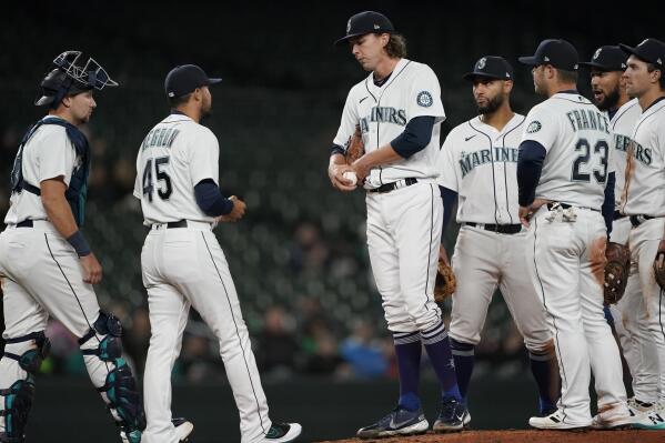 Seattle Mariners starting pitcher Logan Gilbert, center, waits for acting manager Kristopher Negron (45) to take the ball as he is pulled from a baseball game against the Texas Rangers during the seventh inning Wednesday, April 20, 2022, in Seattle. (AP Photo/Ted S. Warren)