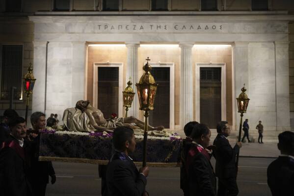 Men carrying the body of Jesus Christ pass the Bank of Greece headquarters during the Epitaph Procession of the Catholic Cathedral Basilica of St Dionysius the Areopagite in Athens, Greece, Good Friday, April 18, 2025. (AP Photo/Thanassis Stavrakis)