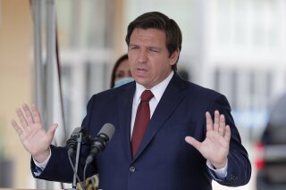 FILE - In this Thursday, May 14, 2020, file photo, Florida Gov. Ron DeSantis speaks at a news conference in Doral, Fla. A federal appellate court has stayed a lower court ruling that gave impoverished Florida felons the right to vote. The order issued Wednesday, July 1, 2020, disappointed voting rights activists and could have national implications in November's presidential election. In May, a federal judge ruled that Florida law can’t stop disenfranchised felons from voting because they can’t pay back any legal fees and restitution they owe. DeSantis immediately appealed to the Atlanta-based 11th U.S. Circuit Court of Appeals, requesting a stay of the ruling and a review of the case by the full appeals court. (AP Photo/Lynne Sladky, File)