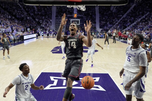 El delantero de Oklahoma, Jalon Moore (14), supera al guardia del estado de Kansas, Tylor Perry (2) y al guardia Cam Carter (5) para encestar el balón durante la primera mitad de un juego de baloncesto universitario de la NCAA el martes 30 de enero de 2024 en Manhattan, Kansas. (Foto AP/Charlie Riedel)