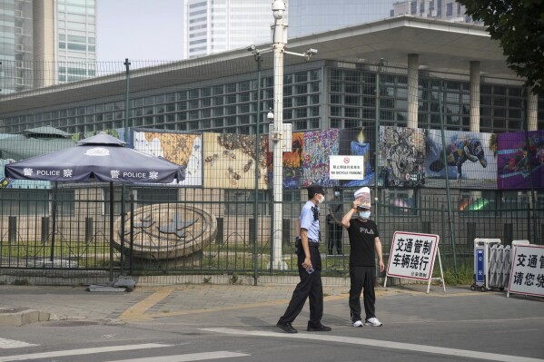 Uniformed and plainclothes security officers stand guard outside the U.S. Embassy in Beijing, Aug. 3, 2022. (AP Photo/Mark Schiefelbein, File)