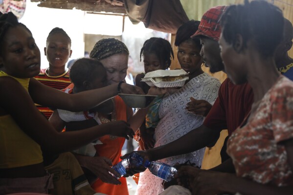 Women scuffle for plates of food for their children at a shelter for families displaced by gang violence, in Port-au-Prince, Haiti, Friday, March 22, 2024. (AP Photo/Odelyn Joseph)