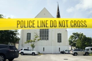 FILE - In this June 19, 2015 file photo, police tape surrounds the parking lot behind the AME Emanuel Church as FBI forensic experts work the crime scene, in Charleston, S.C.Convicted Charleston church shooter Dylann Roof was given nine consecutive life sentences in prison after he pleaded guilty to state murder charges Monday, March 29, 2021 leaving him to await execution in a federal prison and sparing his victims and their families the burden of a second trial.(AP Photo/Stephen B. Morton, File)