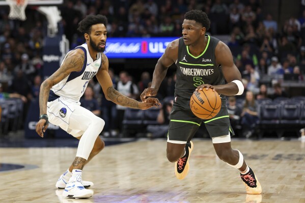 Minnesota Timberwolves guard Anthony Edwards (5) works toward the basket as Dallas Mavericks forward Derrick Jones Jr., left, defends during the second half of an NBA basketball game, Thursday, Dec. 28, 2023, in Minneapolis. (AP Photo/Matt Krohn)