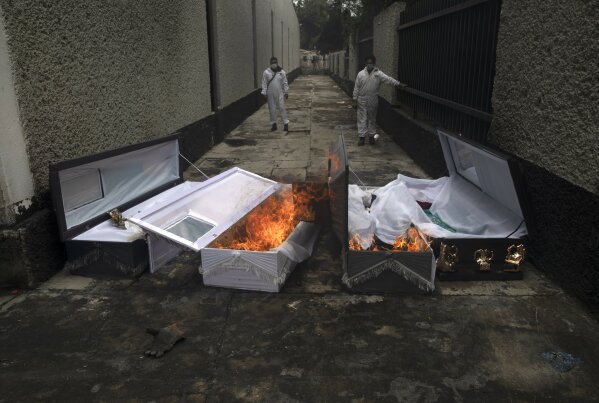 FILE - In this June 24, 2020 file photo, crematorium workers burn the coffins that contained the remains of people who died from the coronavirus after their cremation at the San Nicolas Tolentino cemetery in the Iztapalapa neighborhood of Mexico City. As Mexico approaches 200,000 in officially test-confirmed deaths from COVID-19, the real death toll is probably higher due to the country’s extremely low rate of testing. (AP Photo/Marco Ugarte, File)