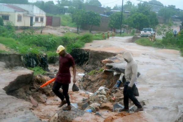 People make their way along a damaged section of a road in Nampula Province, Mozambique, Saturday, March 12, 2022. Officials in Mozambique say that Cyclone Gombe has flooded large areas of northern and central Mozambique, killing more than 10 people. (AP Photo)
