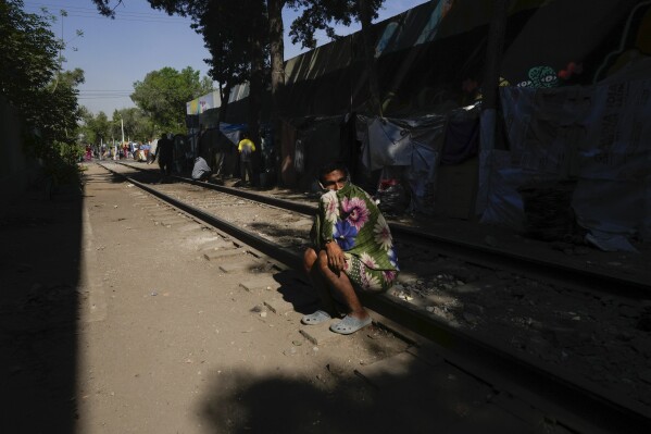 A migrant from Maracaibo, Venezuela, sits on a railroad track lined by makeshift tents where migrants take refuge in Mexico City, Tuesday, March 26, 2024. (AP Photo/Fernando Llano)