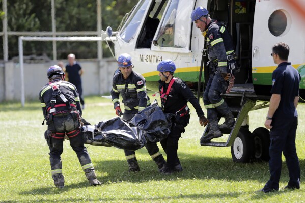 Rescue workers carry the body of a victim of landslide near Shovia, bout 140 kilometers (85 miles) northwest of the capital Tbilisi, Georgia, Friday, Aug. 4, 2023. At least seven people were killed and more than 30 are missing after a landslide hit a resort area in the mountains of the country of Georgia, officials and news reports said Friday. (AP Photo/Zurab Tsertsvadze)