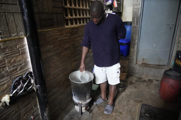 A Kenyan uses charcoal to heat water to take bath as there was no electricity Saturday, Aug. 26 2023. Much of Kenya remains without electricity Saturday morning after an unexplained power outage Friday night shut down the country's main international airport and led to a rare public apology by a government minister.(AP Photo/Abdul Azim Sayyid)