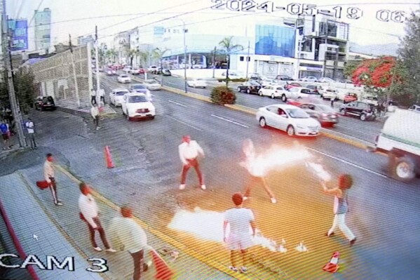 In this image taken from video provided by Jorge Toscano, a flame-swallower, right, and a group of guitar-toting mariachis fight, Sunday, May 19, 2024 in Morelia, Mexico. (Jorge Toscano via AP)