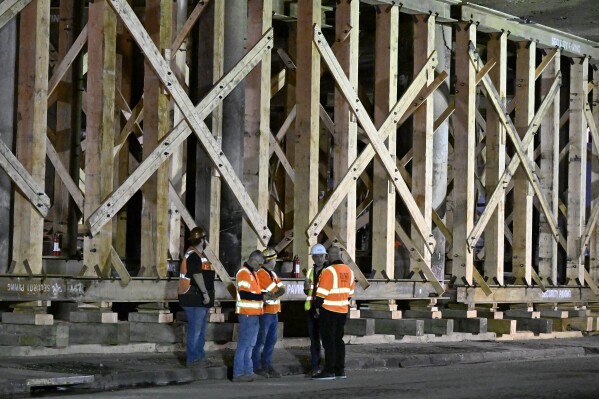 Construction workers gather at the repairs to the I-10 freeway, which was closed by an underpass fire on Saturday, Nov. 11, 2023, in Los Angeles, Sunday, Nov. 19. (AP Photo/Alex Gallardo)