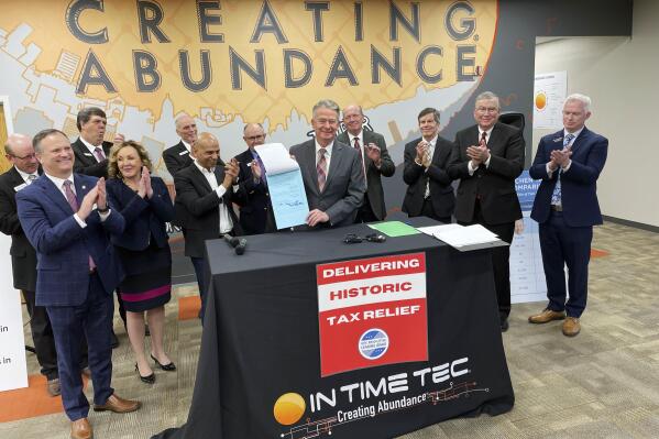 Idaho Gov. Brad Little, center, poses for photos with In Time Tec CEO Jeet Kumar, middle left, and Republican leaders from the House and Senate, and after he signed into law a $600 million tax cut, the biggest tax cut in the state's history, at software company In Time Tec in Meridian, Idaho, Friday, Feb. 4, 2022. (AP Photo/Keith Ridler)