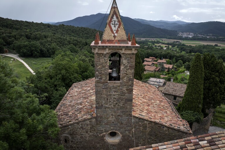 View of the bell tower of the12th-century Sant Romà church, where students of the Vall d'en Bas School of Bell Ringers perform playing bells, at the tiny village of Joanetes, about two hours north of Barcelona, Spain, Saturday, June 29, 2024. A school set up to revive the manual ringing of church bells has graduated its first class of 18 students after learning their ringing skills. (AP Photo/Emilio Morenatti)