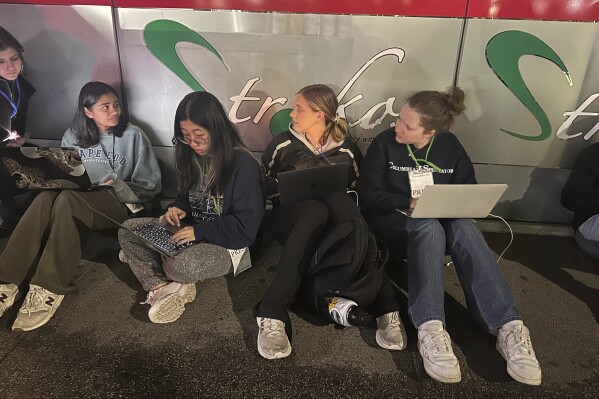 Jóvenes del periódico estudiantil Columbia Daily Spectator trabajan durante la noche mientras la policía desaloja a manifestantes del campus de la Universidad de Columbia, el martes 30 de abril de 2024, en Nueva York. (AP Foto/Jake Offenhartz)