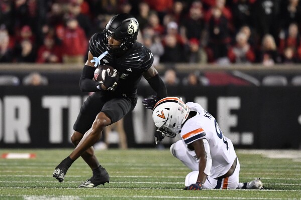 Louisville wide receiver Jimmy Calloway, left, avoids a tackle-attempt by Virginia safety Coen King, right, during the first half of an NCAA college football game in Louisville, Ky., Thursday, Nov. 9, 2023. (AP Photo/Timothy D. Easley)