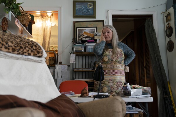 FILE - Nancy Rose, who contracted COVID-19 in 2021 and exhibits long-haul symptoms including brain fog and memory difficulties, pauses while organizing her desk space, Tuesday, Jan. 25, 2022, in Port Jefferson, N.Y. Rose, 67, said many of her symptoms waned after she got vaccinated, though she still has bouts of fatigue and memory loss. U.S. health officials estimate 3.3 million Americans have chronic fatigue syndrome — a bigger number than previous studies have suggested, and one likely boosted by patients with long COVID, according to results released by the Centers for Disease Control and Prevention on Friday, Dec. 8, 2023. (AP Photo/John Minchillo, File)