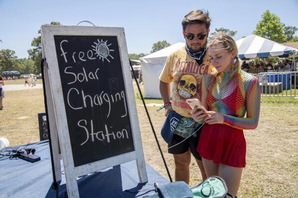 Festivalgoers use the free solar charging station at the Bonnaroo Music and Arts Festival on Saturday, June 18, 2022, in Manchester, Tenn. (Photo by Amy Harris/Invision/AP)