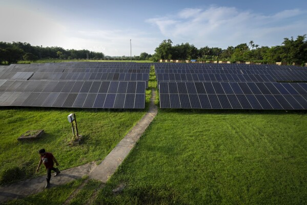 An employee walks away from solar panels near a hydrogen plant at Oil India Limited in Jorhat, India, Thursday, Aug. 17, 2023. (AP Photo/Anupam Nath)