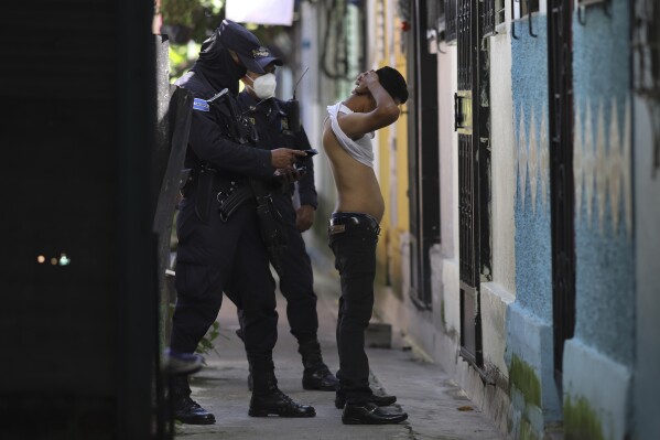 FILE - A police officer searches and checks the documents of a man living in the Kiwanis Community, during a preventive patrol in search of gang members in Soyapango, El Salvador, Tuesday, Aug. 16, 2022. A May 2023 report by the human rights organization Cristosal, tallied 153 incarceration deaths during the first year of the state of emergency in El Salvador. No victim had been convicted of the alleged crime that put them behind bars. (AP Photo/Salvador Melendez, File)