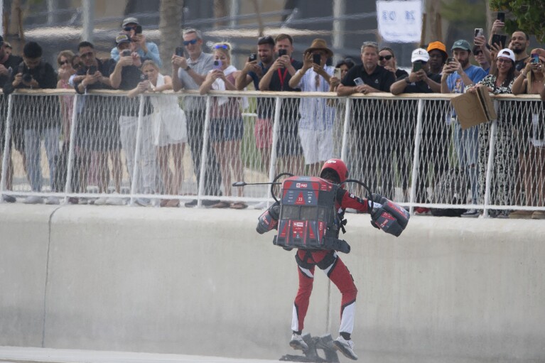 A jet suit pilot lands in Dubai, United Arab Emirates, Wednesday, Feb. 28, 2024. Dubai on Wednesday hosted what it called its first-ever jet suit race. Racers zipped along a route with the skyscrapers of Dubai Marina looming behind them, controlling the jet engines on their hands and their backs. (AP Photo/Jon Gambrell)
