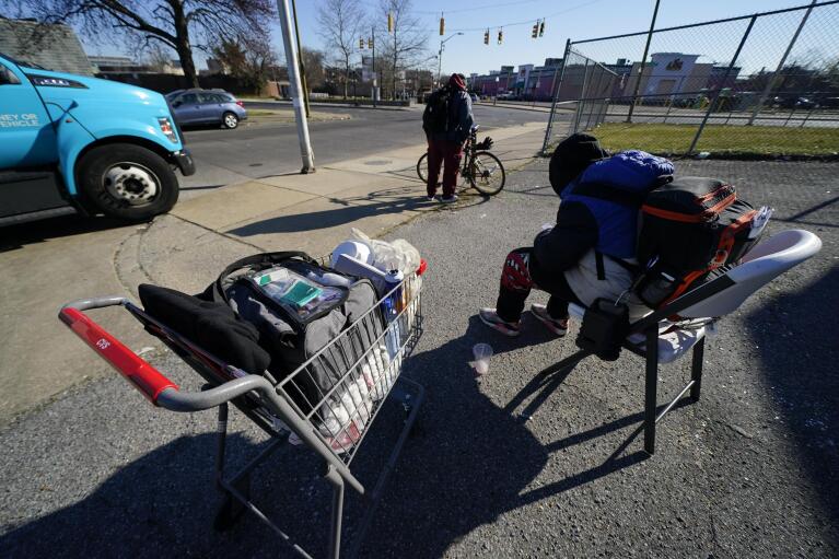 A patient's belongings are seen on a shopping cart, left, as he is treated inside a Baltimore City Health Department RV, Monday, March 20, 2023, in Baltimore. The Baltimore City Health Department's harm reduction program uses the RV to address the opioid crisis, which includes expanding access to medication assisted treatment by deploying a team of medical staff to neighborhoods with high rates of substance abuse and offering buprenorphine prescriptions. (AP Photo/Julio Cortez)