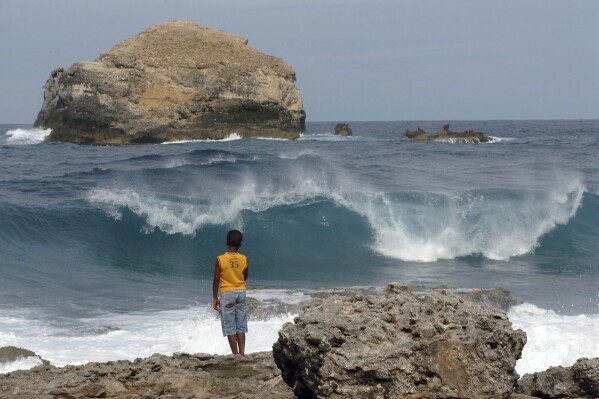 FILE - A youth watches the waves crash along the shores of Pointe-des-Chateaux on the Caribbean island of Guadeloupe, Wednesday, Sept. 2, 2009. U.N. independent experts are denouncing chronic water cuts in the French Caribbean island of Guadeloupe, Friday, March 29, 2024, adding that they are concerned about tap water pollution, excessive prices and attempts to silence critics.(AP Photo/Dominique Chomereau-Lamotte, File)
