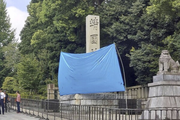 A blue sheet covers a stone pillar on which graffiti was found at Yasukuni Shrine in Tokyo Monday, Aug. 19, 2024. (Kyodo News via AP)