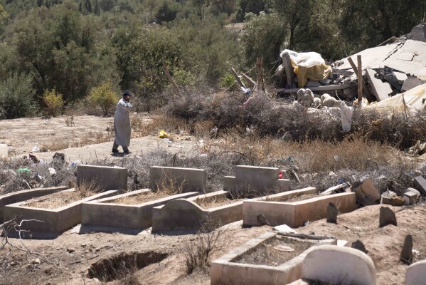 A man walks past a cemetery where people who were killed by the earthquake were buried, in the village of Tafeghaghte, near Marrakech, Morocco, Monday, Sept. 11, 2023. (AP Photo/Mosa'ab Elshamy)