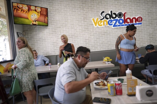 Clientes comen dentro de uno de los restaurantes de Sabor Venezolano, propiedad de Wilmer Escaray, que gestiona una docena de negocios que contratan a migrantes venezolanos como fue él en su día, en Doral, Florida, el martes 1 de abril de 2025. (AP Foto/Rebecca Blackwell)