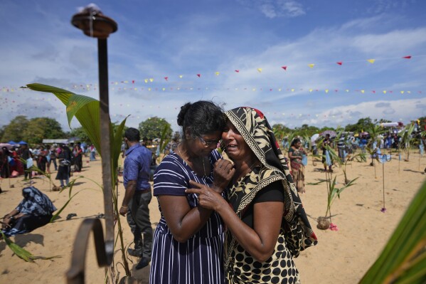 A Sri Lankan Tamil war survivor is consoled by another as she cries for her deceased family members during a remembrance ceremony on a small strip of land where thousands of civilians were trapped during the last stages of the country's civil war in Mullivaikkal, Sri Lanka, Saturday, May 17, 2024. Ethnic Tamils commemorated the 15th anniversary of the bloody end to Sri Lanka's civil war, lighting lamps and offering flowers at the site where thousands of people are said to have been killed and maimed in the final stages of the fighting. (AP Photo/Eranga Jayawardena)