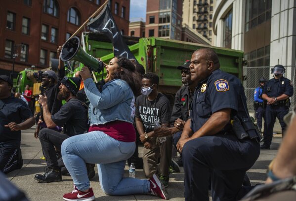 Protest organizer Alyssa Bates, left, kneels beside Grand Rapids police Chief Eric Payne during a protest in downtown Grand Rapids, Mich., Wednesday, June 3, 2020, prompted by the death of George Floyd. (Anntaninna Biondo/The Grand Rapids Press via AP)