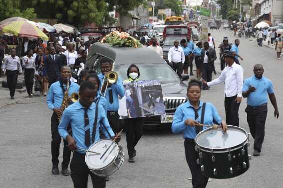A funeral procession for mission director Judes Montis, killed by gangs alongside two of his U.S. missionary members, makes its way to the cemetery after his funeral ceremony in Port-au-Prince, Haiti, Tuesday, May 28, 2024. The service also honored the lives of Davy and Natalie Lloyd, a married couple in their early 20s who was with Montis when gunmen ambushed them on Thursday night, May 23, as they left a youth group activity held at a local church. (AP Photo/Odelyn Joseph)