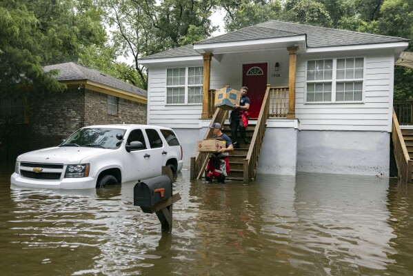Savannah Fire Advanced Firefighters Ron Strauss, top, and Andrew Stevenson, below, carry food to residents in the Tremont Park neighborhood that where stranded in stormwater from Tropical Storm Debby, Tuesday, Aug. 6, 2024, in Savannah, Ga. (AP Photo/Stephen B. Morton)