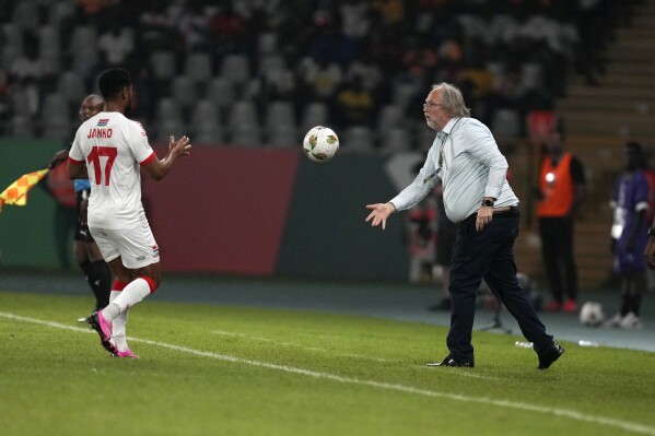 Gambia's head coach Tom Saintfiet, right, throws the ball to his player Saidy Janko during the African Cup of Nations Group C soccer match between Guinea and Gambia, at the Charles Konan Banny stadium in Yamoussoukro, Ivory Coast, Friday, Jan. 19, 2024. (AP Photo/Sunday Alamba)
