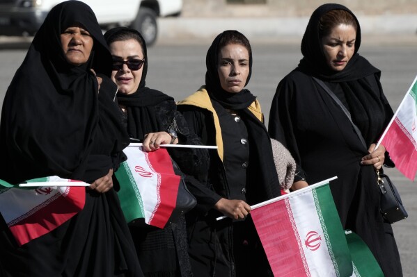 Holding Iranian flags, people attend the funeral ceremony of the victims of Wednesday's bomb explosion in the city of Kerman about 510 miles (820 kms) southeast of the capital Tehran, Iran, Friday, Jan. 5, 2024. Iran on Friday mourned those slain in an Islamic State group-claimed suicide bombing targeting a commemoration for a general slain in a U.S. drone strike in 2020. (AP Photo/Vahid Salemi)