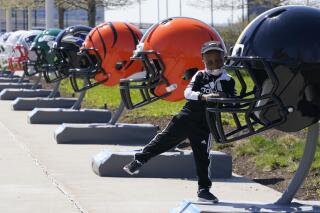 Joseph Toliver, 4, plays on one of the 32 NFL team helmets on display, Tuesday, April 13, 2021, in downtown Cleveland. Forced to cancel last year's NFL Draft in Las Vegas, the league is using lessons learned while plowing through an unprecedented, socially-distanced 2020 season and holding the Super Bow in Tampa, to have a draft that will look much more like normal — well, the new normal — with fans wearing their favorite team's colors and required masks.(AP Photo/Tony Dejak)