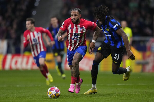 Atletico Madrid's Memphis Depay, left, runs with the ball past Inter Milan's Yann Aurel Bisseck during the Champions League, round of 16, second leg soccer match between Atletico Madrid and Inter Milan at the Metropolitano stadium in Madrid, Spain, Wednesday, March 13, 2024. (AP Photo/Manu Fernandez)