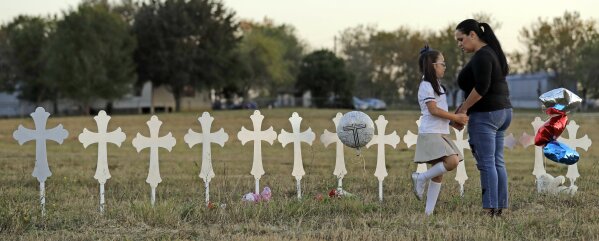 
              Meredith Cooper, right, and her daughter Heather, 8, visit a line of crosses before a vigil for the victims of the First Baptist Church shooting, Monday, Nov. 6, 2017, in Sutherland Springs, Texas. A man opened fire inside the church in the small South Texas community on Sunday, killing more than 20 and injuring others. (AP Photo/David J. Phillip)
            